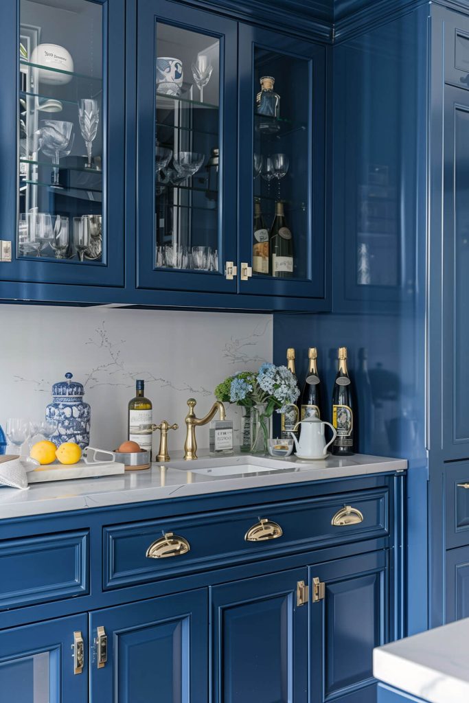 Deep navy blue kitchen cabinets providing a bold contrast in a chic kitchen with brass hardware and light countertops.