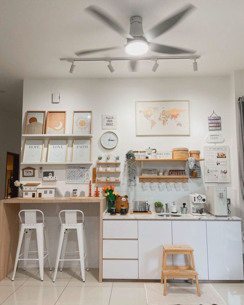 Eclectic coffee bar with a gallery wall, white cabinetry, compact counter area, framed prints, and practical bar stool setup.