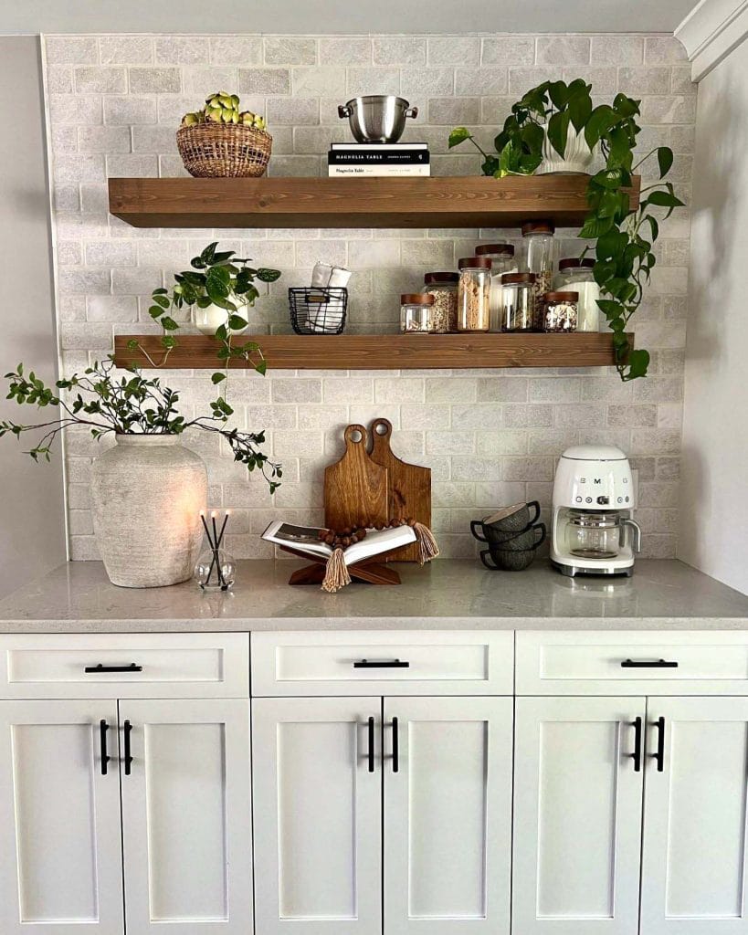 Coffee bar with open shelving displaying mugs, glasses, and coffee essentials against a clean white backdrop.