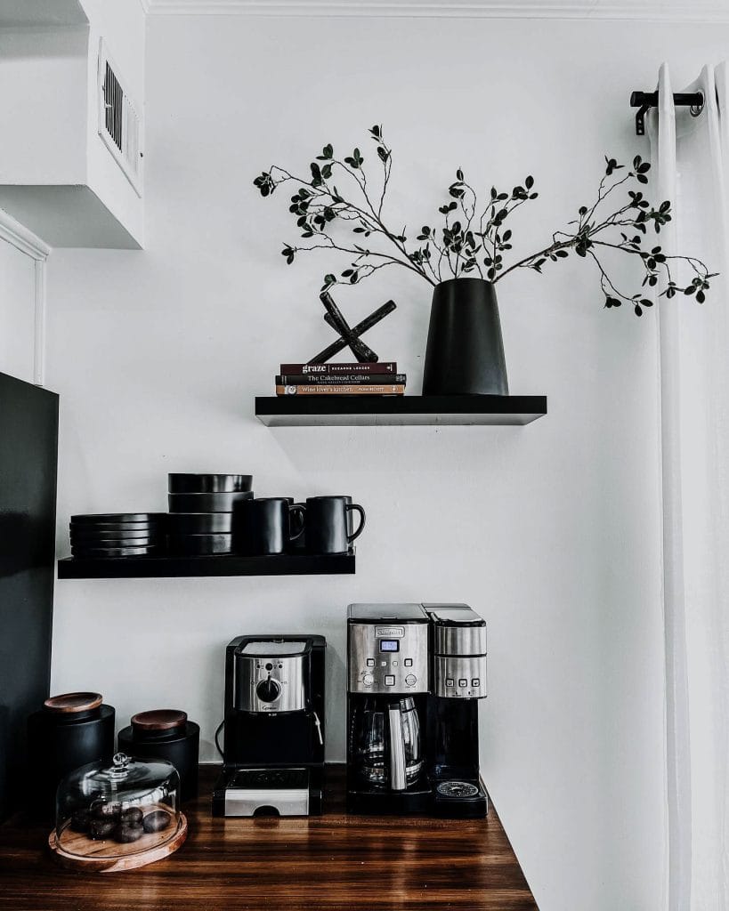 Sophisticated coffee corner with dark wood and black elements, sleek espresso machine, and black ceramic mugs.