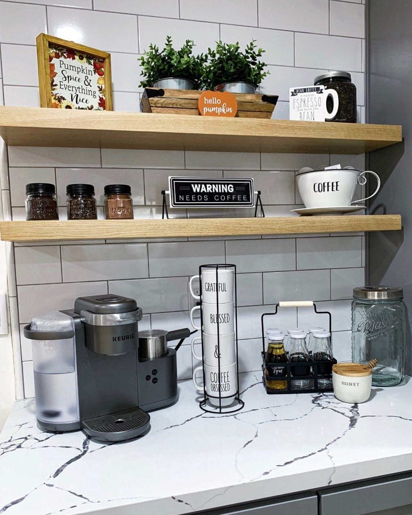 Bright and cheerful coffee bar with white cabinetry, open shelving, playful decorative items, and plants.