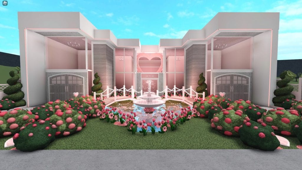 A beautiful blush-colored mansion with a grand entrance, a heart-shaped fountain, and well-kept gardens.