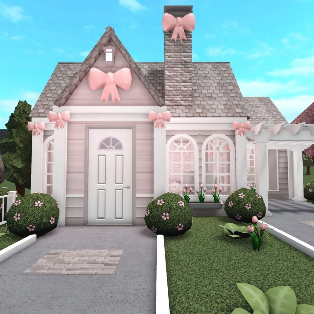 A charming pink cottage with decorative bows and a whimsical garden, creating a cute and inviting look.