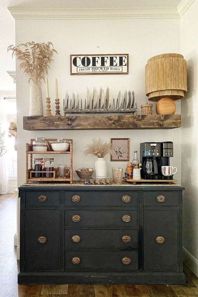 Rustic coffee bar with distressed black dresser, natural wood accents, open shelf, and vintage-modern coffee essentials.