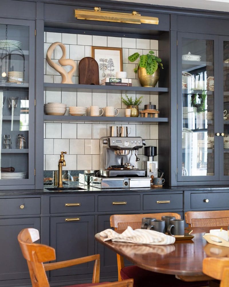 Sophisticated coffee station with navy-blue cabinetry, marble countertops, brass hardware, and integrated appliances.