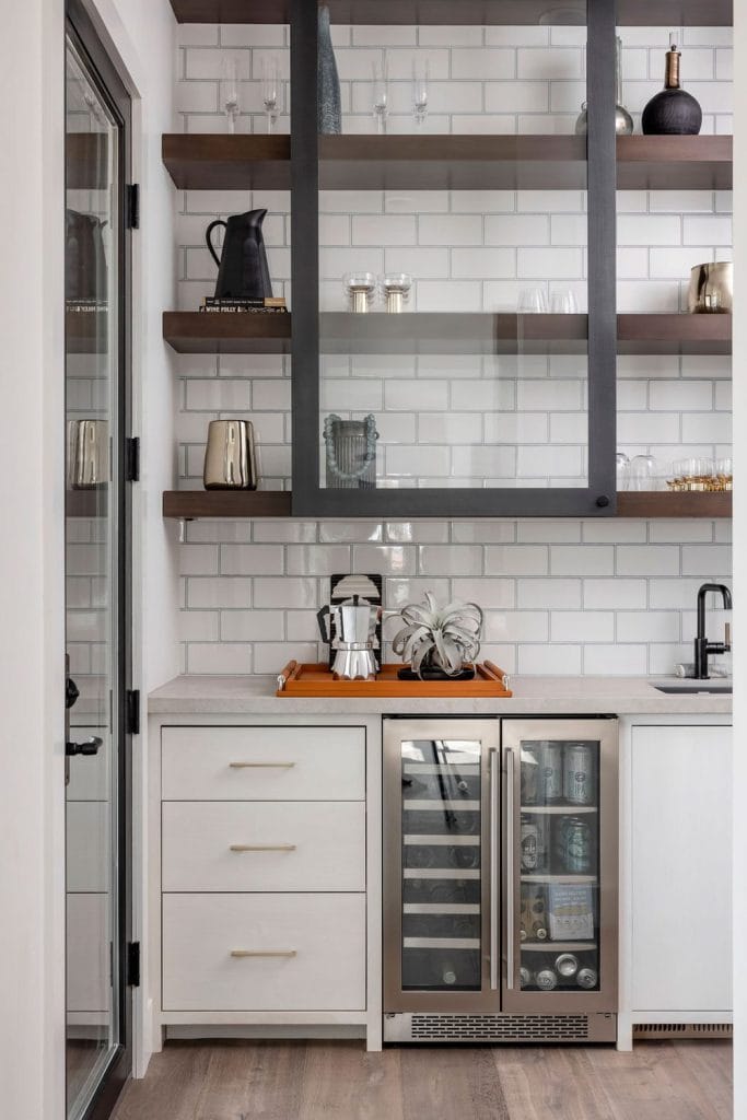 Stylish marble countertop with mini-fridge, plant, and sleek white kettle for modern coffee preparation.