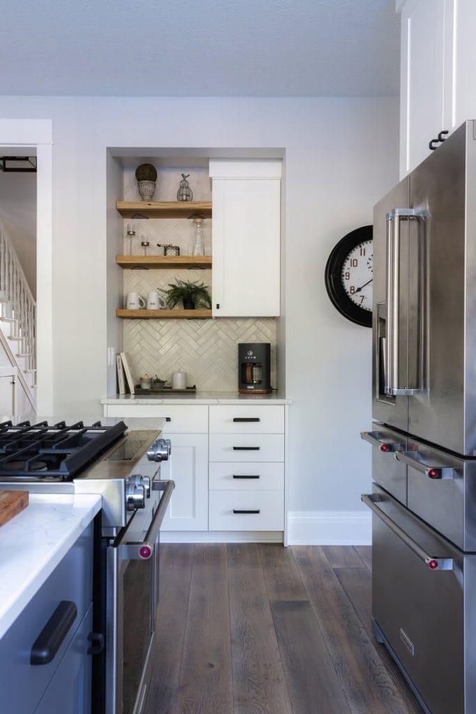 Asymmetrical coffee nook with dark wooden shelves, white cabinetry, and eclectic mix of decor items.