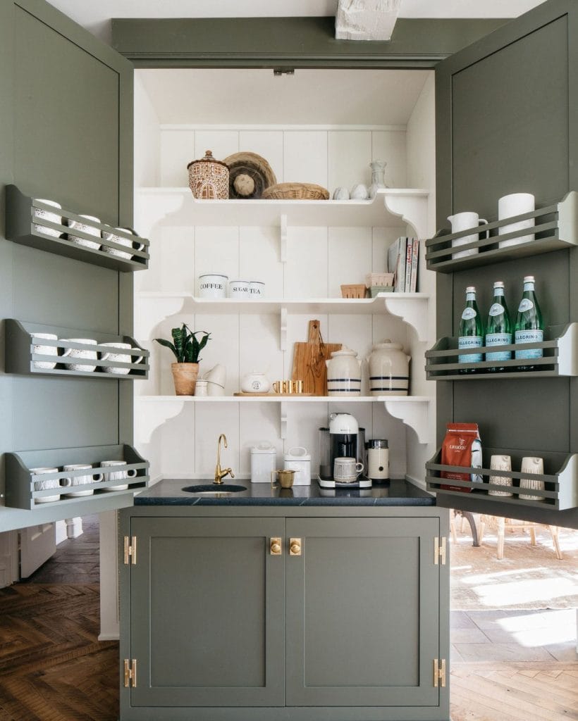 High-end coffee station with white cabinetry, brass accents, and rich wooden elements in a luxurious kitchen corner.