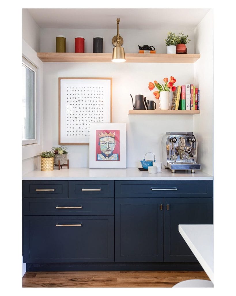 Clean and organized coffee setup with light wooden shelves, canisters, and glossy backsplash tiles.