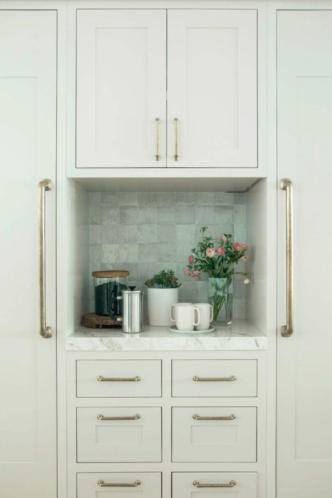 Coastal-themed coffee bar featuring white cabinetry, a marble countertop, and fresh floral arrangements creating a beachy atmosphere.