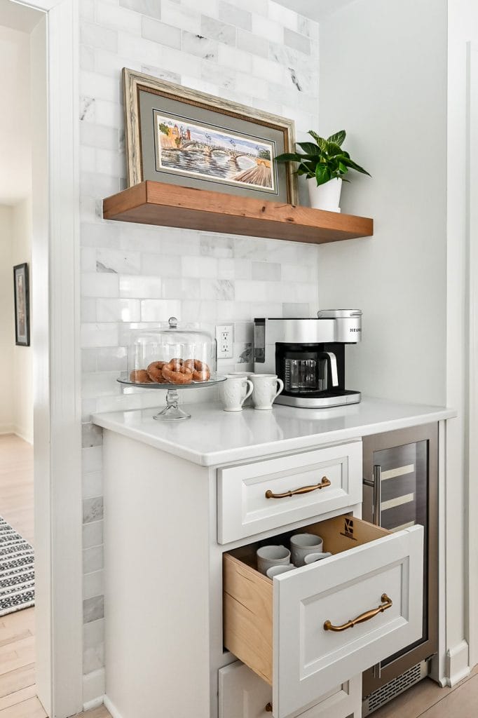 Modern coffee station with clean lines, white cabinetry, dark countertops, and built-in appliances.