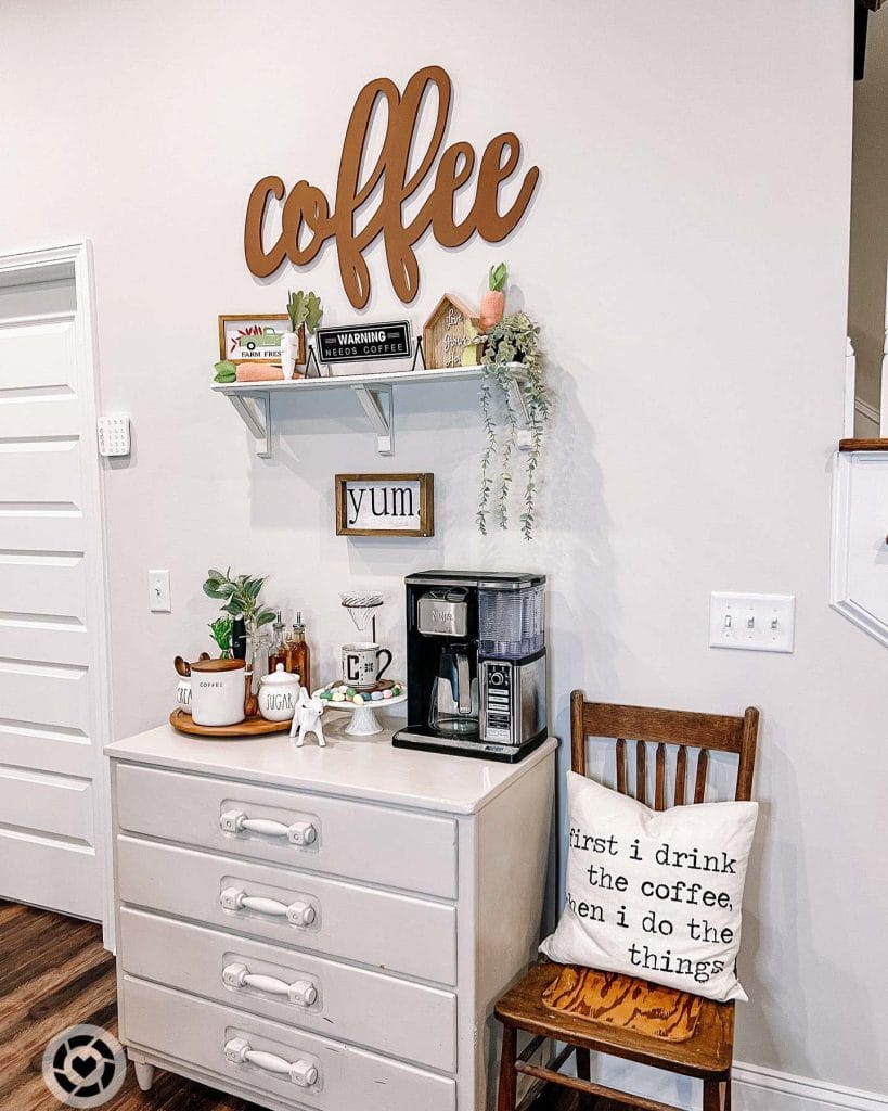 Inviting coffee setup with large "Coffee" sign, decor items, dresser-style counter, and wall-mounted shelf.