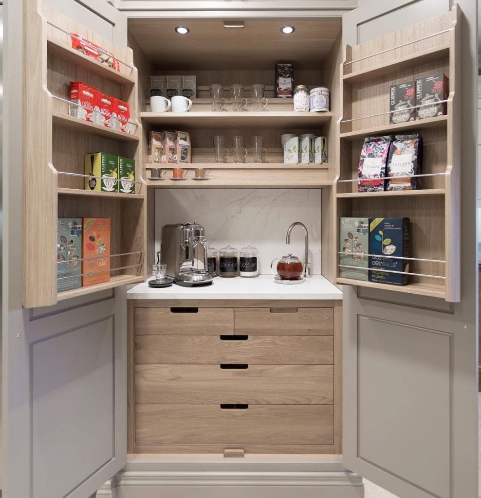 Hidden coffee station with pull-out shelf, ample storage, and light wood finish.