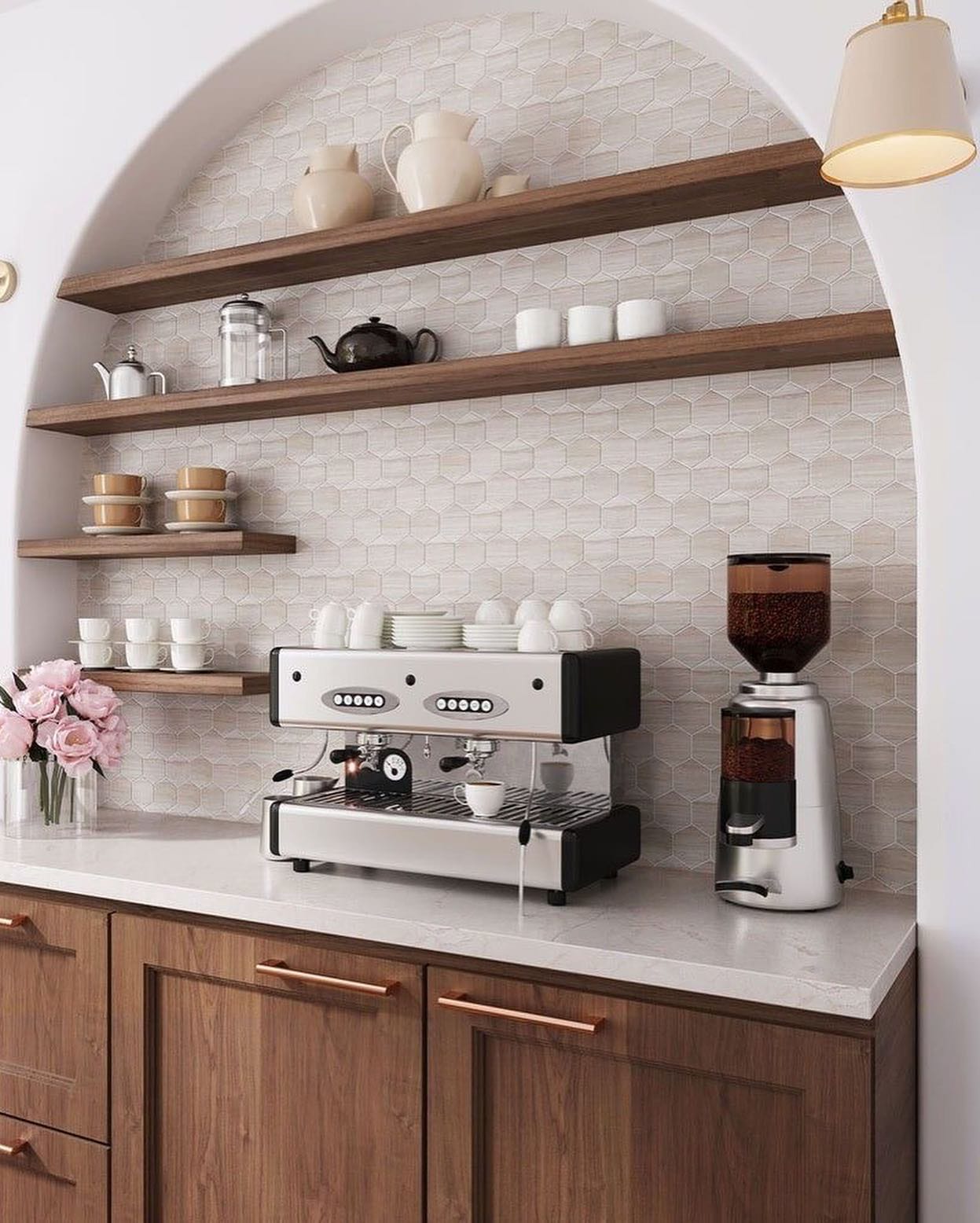 A stylish coffee station nestled within an arched alcove, featuring rich wooden cabinets and shelves. The combination of white hexagonal backsplash tiles and sleek coffee equipment creates a warm and elegant space for brewing coffee.