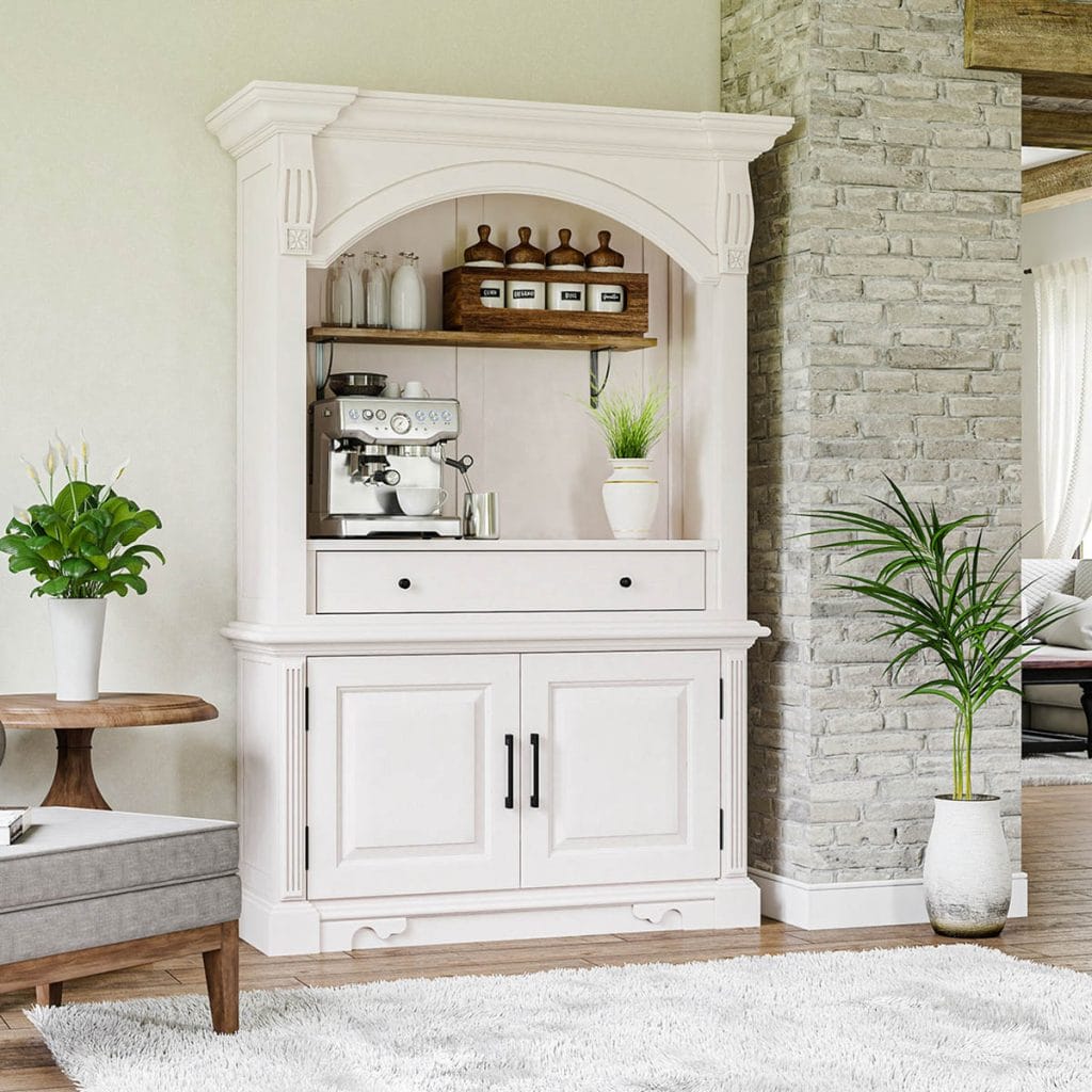 A white hutch with a built-in espresso machine and labeled canisters, set against a stone accent wall. The hutch is adorned with greenery and situated in a cozy living space, enhancing the modern farmhouse aesthetic.