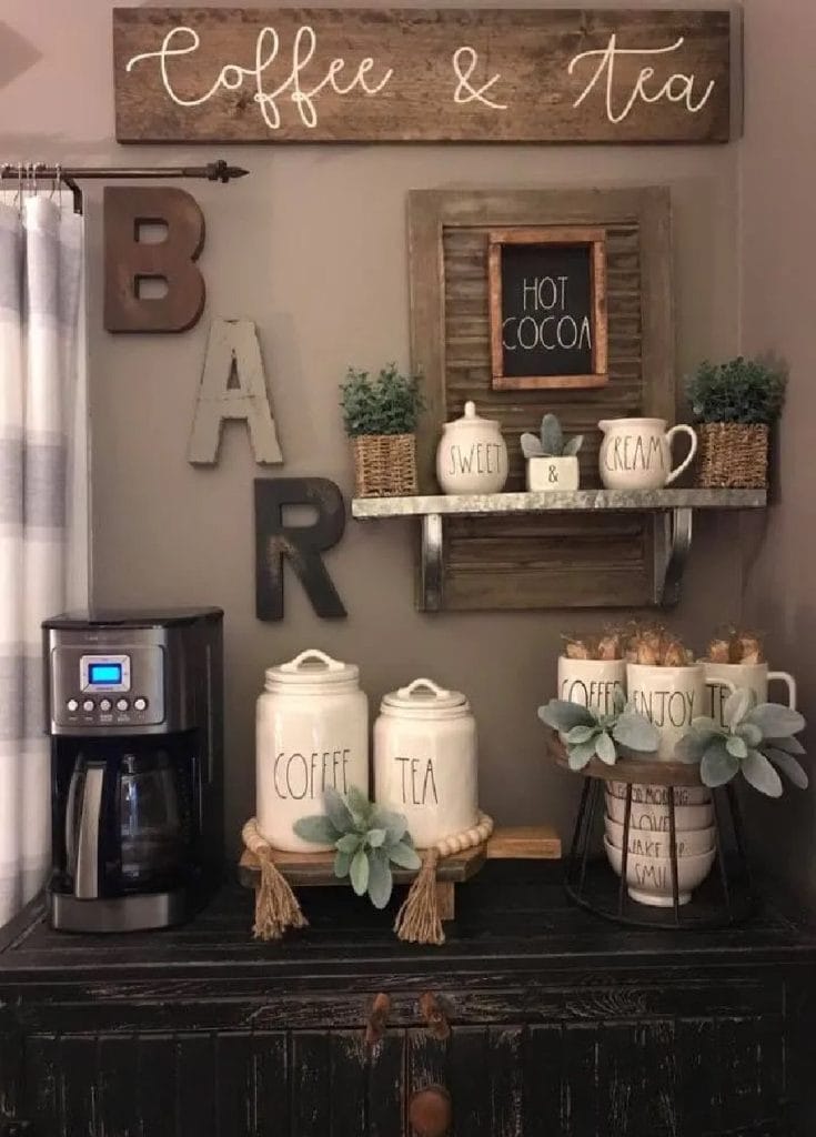 A farmhouse-style coffee bar with white cabinetry, wooden accents, and open shelving displaying mugs and decor, creating a cozy atmosphere.