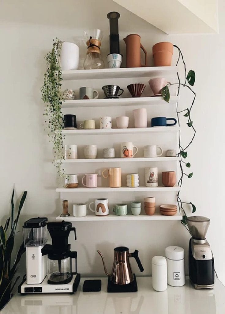 A coffee bar with a stylish display of various mugs on open shelving, adding a playful and personal touch to the space.