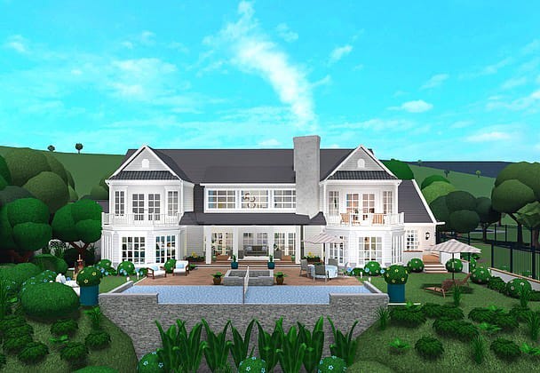 A beautiful house with a bright white exterior, expansive windows, and a lush green lawn, perfect for summer living.