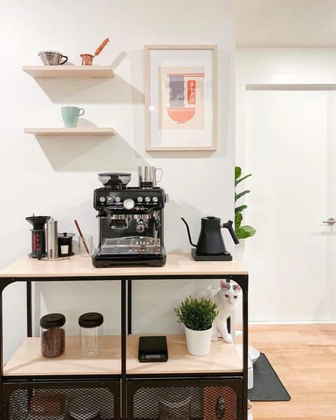 A minimalist coffee station with white cabinetry, a sleek coffee maker, and subtle decor, focusing on simplicity and elegance with clean lines and an uncluttered design.