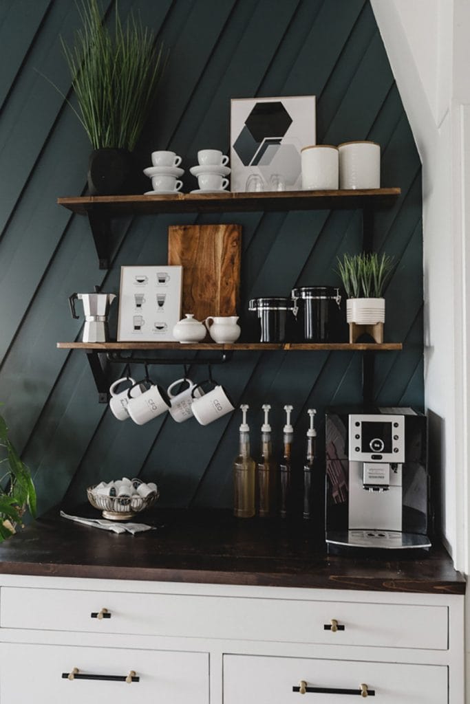 Modern coffee bar with a dark accent wall, white cabinetry, and a sleek coffee machine.