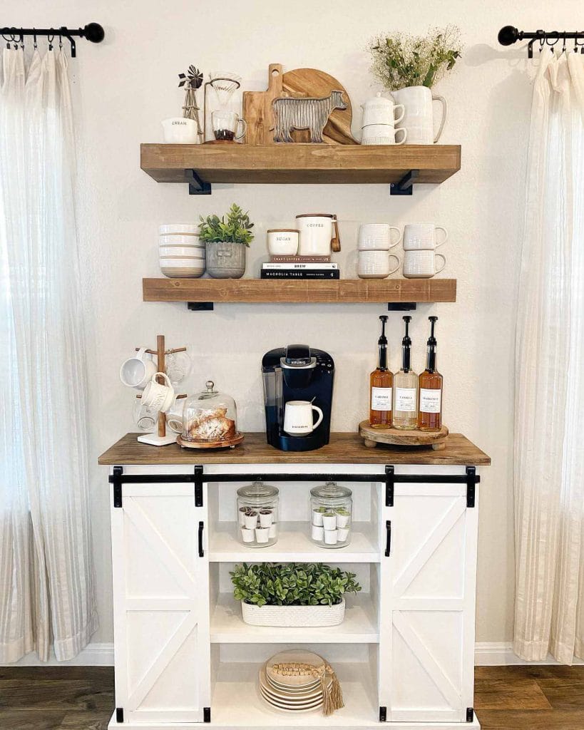 A sophisticated coffee bar with white cabinetry, wooden shelves, and a sleek espresso machine. The minimalist design and gold accents add elegance to the space.