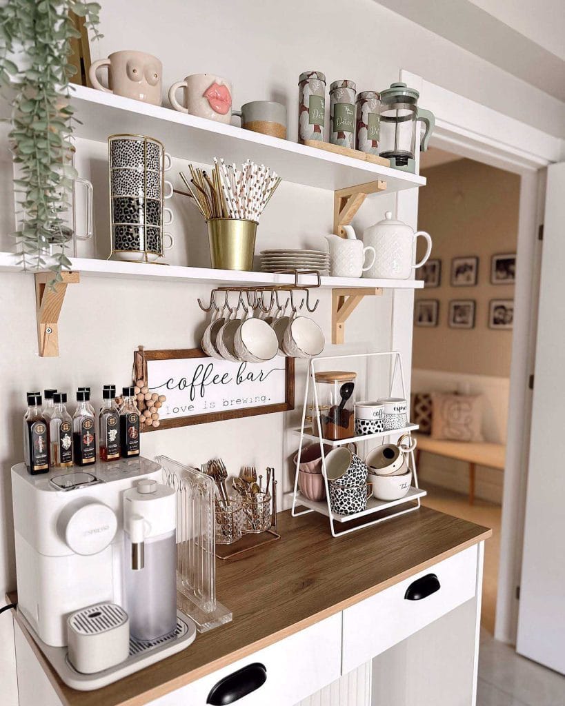 A rustic farmhouse-style coffee bar with white shelves and white cabinetry with charming decor pieces.