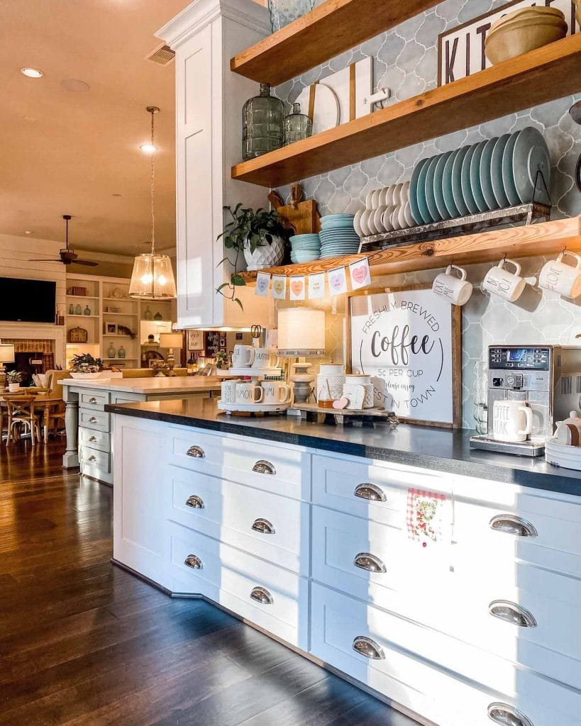 A modern, minimalist coffee bar with a sleek black countertop and floating wooden shelves. The uncluttered design and simple decor create a serene and functional space.