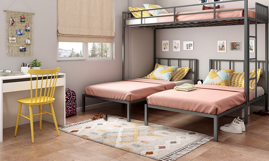 Dorm room with a sleek metal bunk bed for three, featuring a minimalist design with pink and yellow accents.