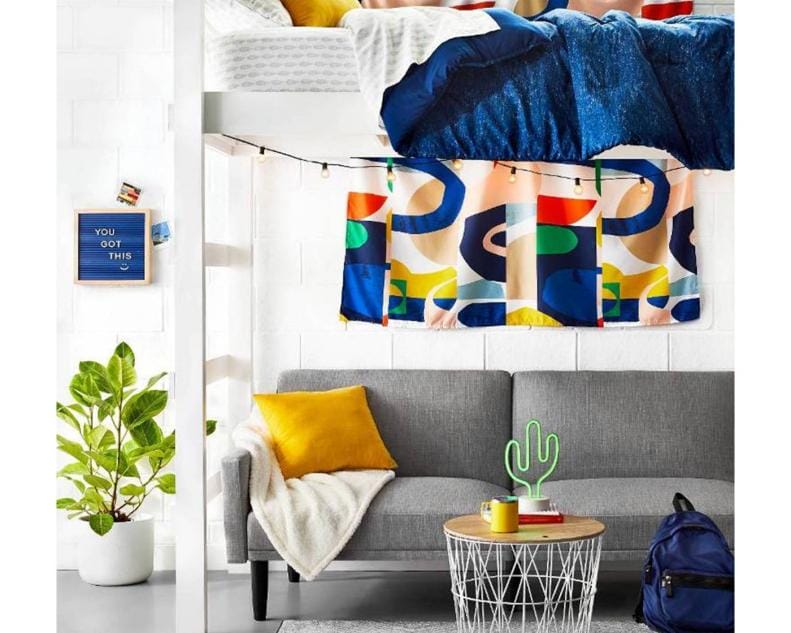 Lofted bed with cozy living space underneath, colorful curtains, and neon cactus lamp.