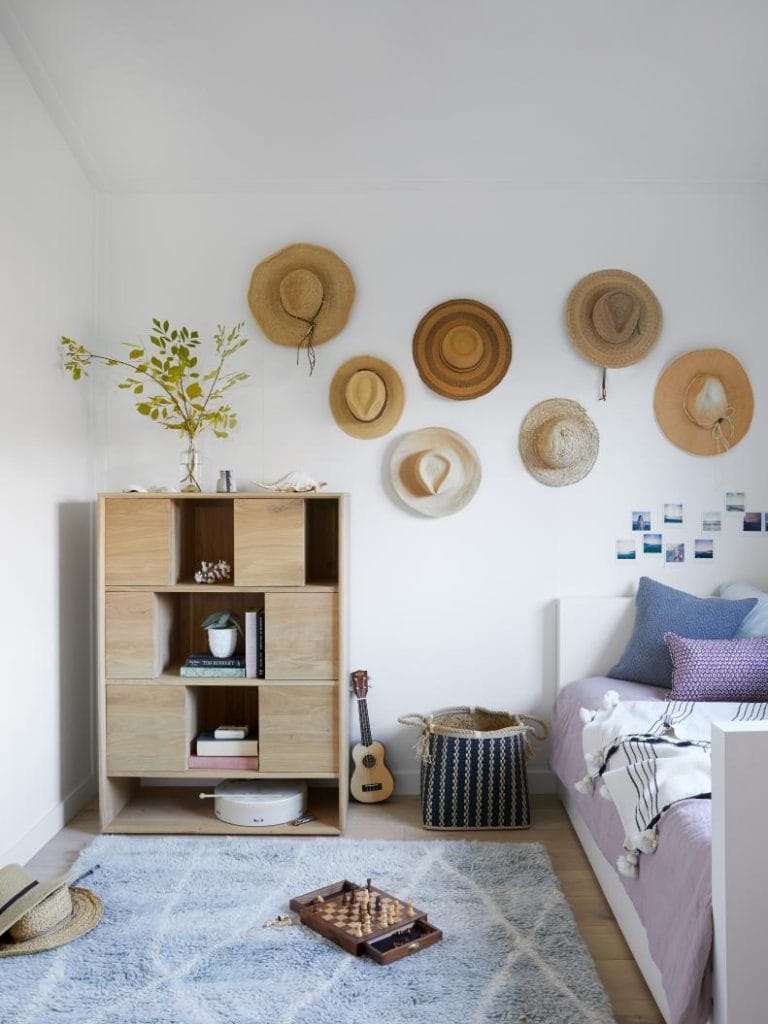 A dorm room with hats displayed on the wall, complemented by cozy decor elements such as a soft rug and woven baskets.