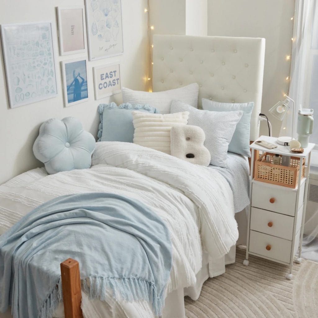 Room with soft blue and white tones, beach-themed wall art, comfy bed, and decorative pillows.