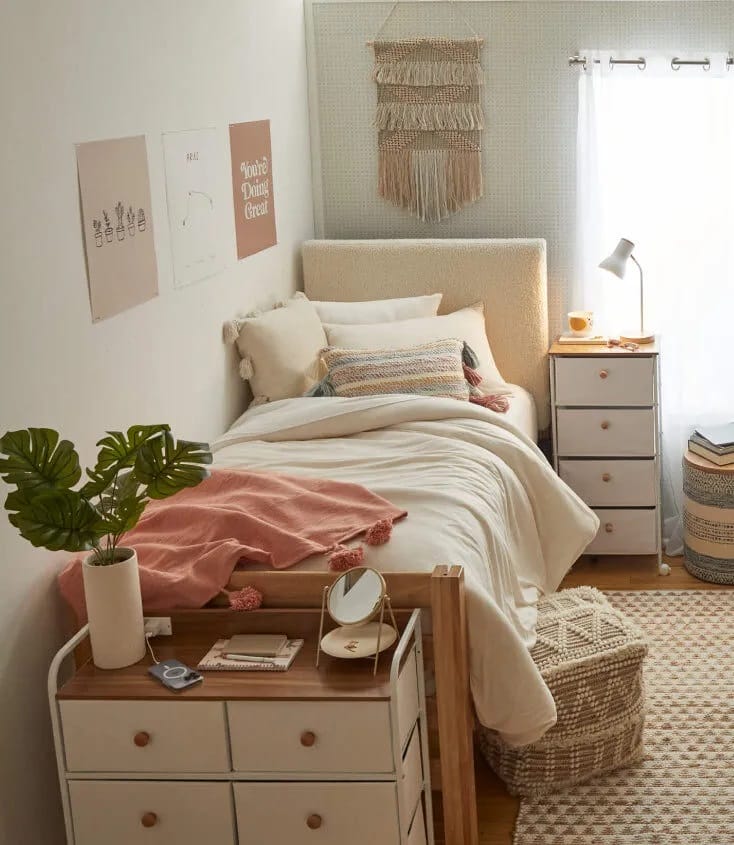 A cozy bedroom with beige and blush bedding, greenery, and woven textures.