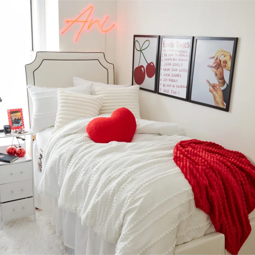 Room with a red and white color scheme, playful decor elements, heart-shaped pillow, and neon sign.