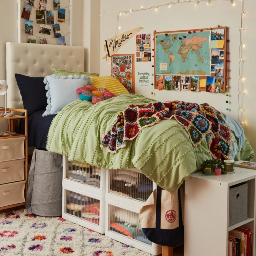 Room with a vibrant green bedspread, multicolored crochet blanket, wall collage, and string lights.