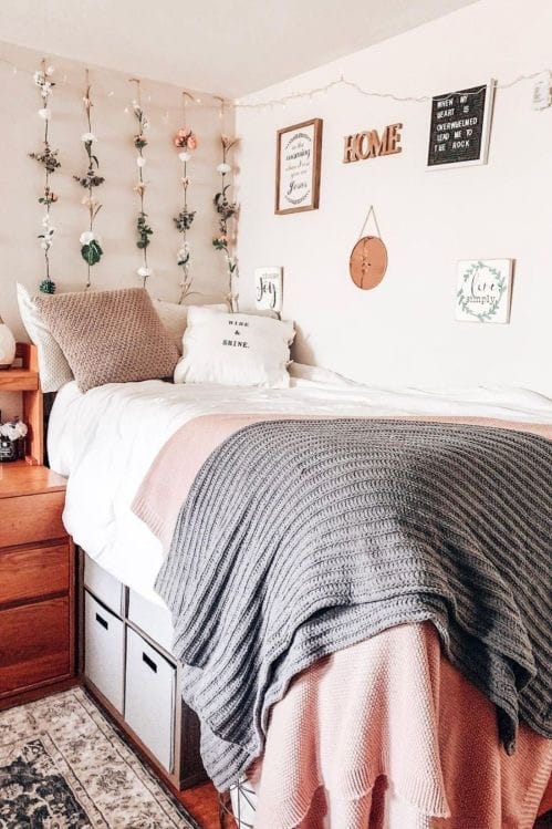 Bed with knitted throw, personalized decor, and floral wall accents.