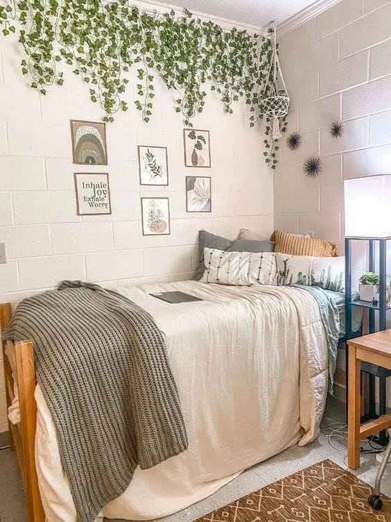 Bed with a mix of green and gray bedding, leafy wall decor, and natural-themed artwork