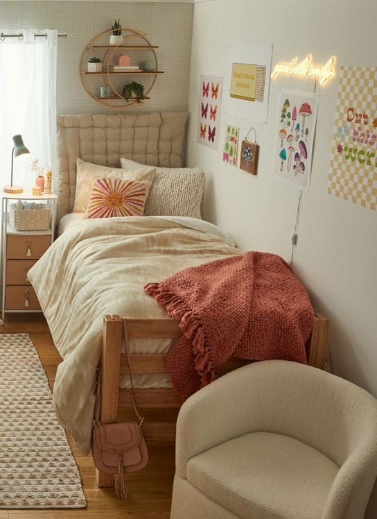 Bed with beige and orange decor, cozy throw blanket, and wall art with inspirational quotes.