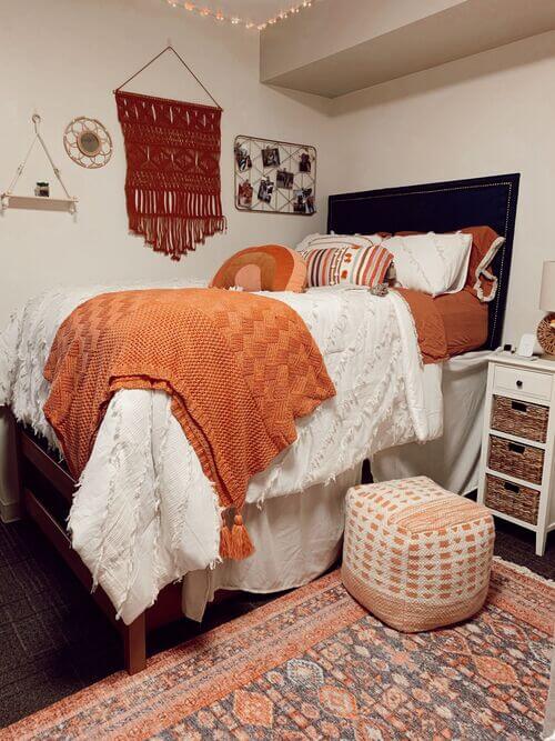 A dorm room with terracotta tones, textured throws, and woven decor, blending modern and bohemian styles.