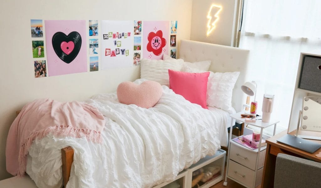 A bed with pink-themed decor, heart-shaped pillows, and cheerful wall art.