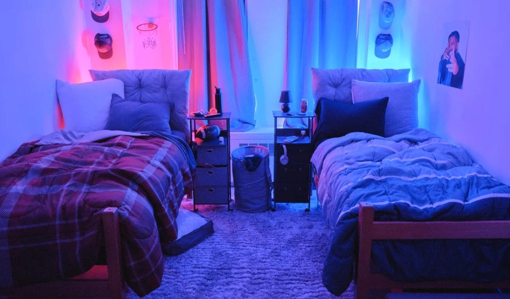 Room with bold neon red and blue lighting, comfortable bed arrangement, and modern decor