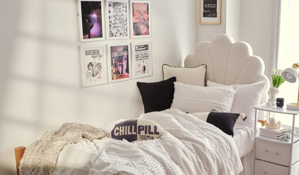 A minimalist room with a scallop-shaped headboard, white bedding, black pillows, and framed wall art for a chic appearance.