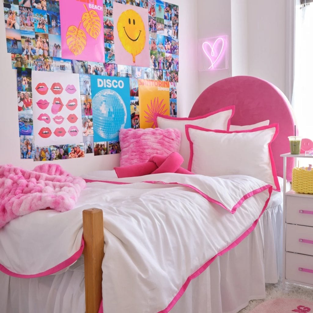 A vibrant room with pink and blue bedding, photo collages, playful decor, and a neon heart sign.