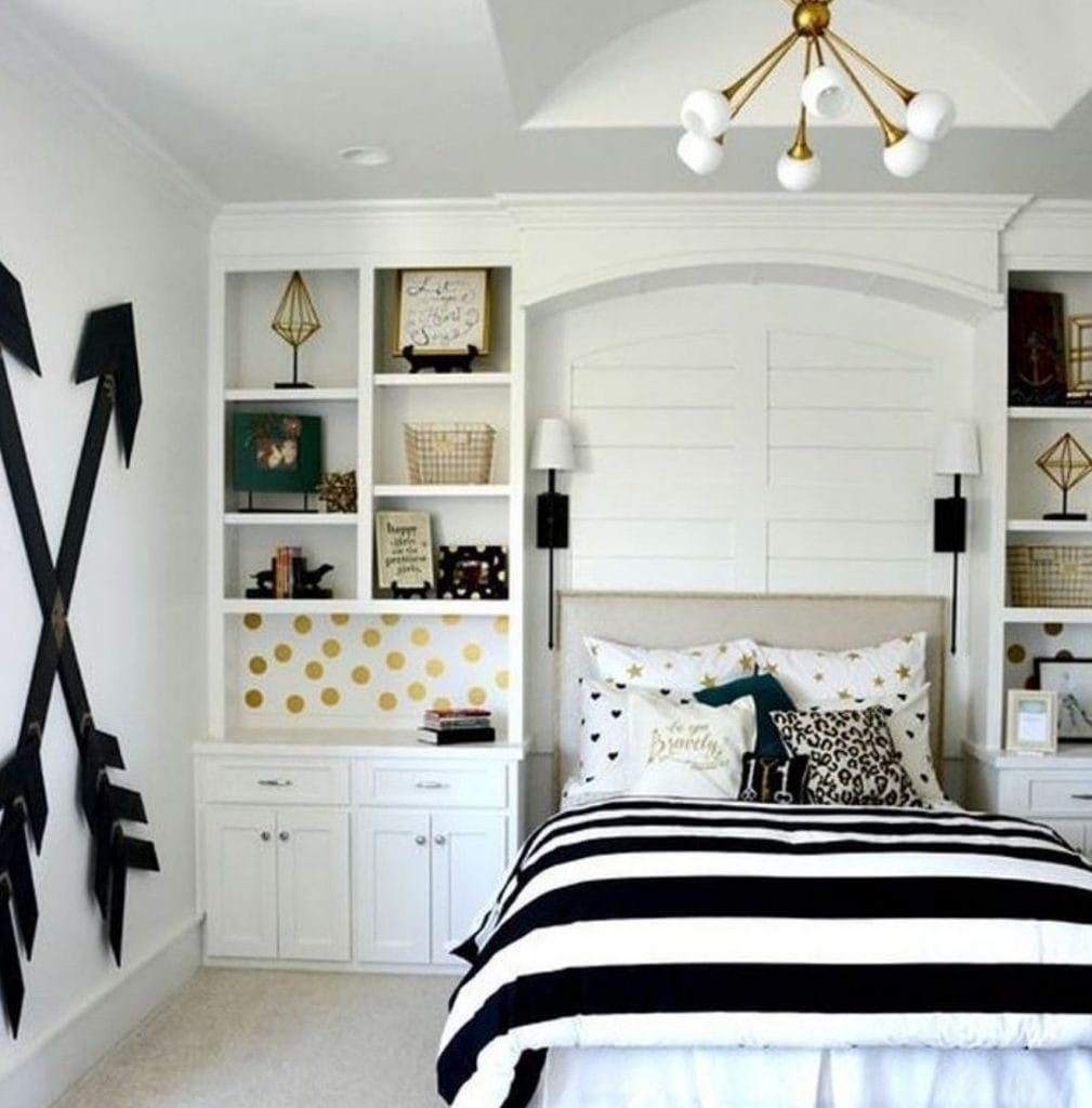 A modern space with black and white striped bedding, a gold polka dot accent wall, and built-in shelving.