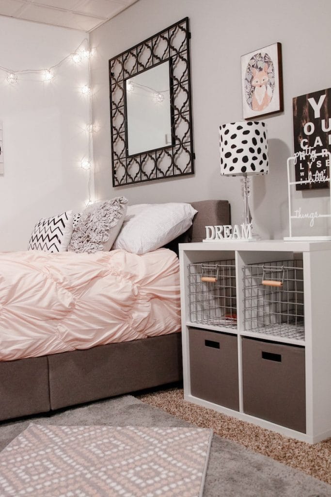 A neutral space with string lights, a patterned rug, and soft bedding.