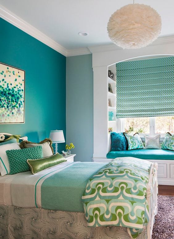 A space with teal walls, a built-in window seat, and a mix of geometric patterns and soft textures.