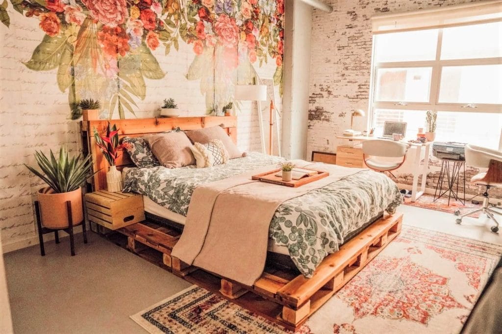 A space with a floral mural, wooden pallet bed, and a mix of rustic and modern decor.