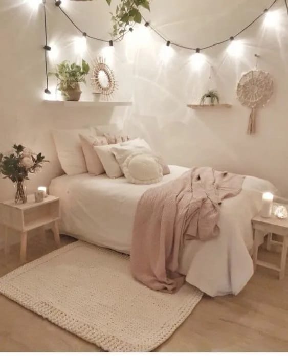 A simple bedroom with string lights, neutral bedding, and cozy decor.