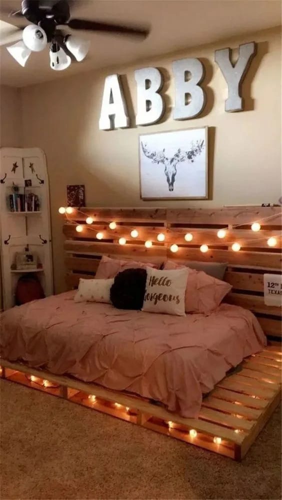 A bedroom with a rustic pallet bed frame, warm lighting, and personalized decor.