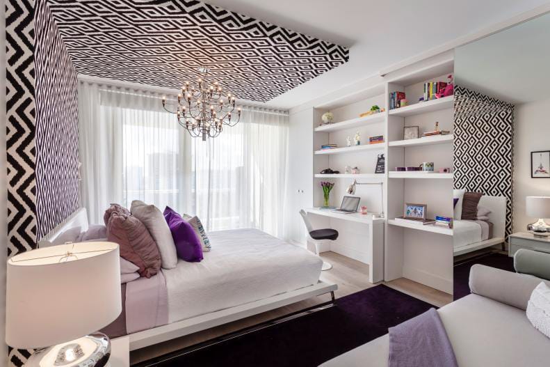 Teen bedroom with black and white geometric patterns, chandelier, and built-in desk and shelves.