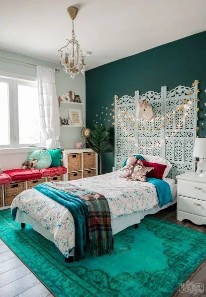 Eclectic bohemian bedroom with a teal rug, intricate headboard, and warm-toned decor.